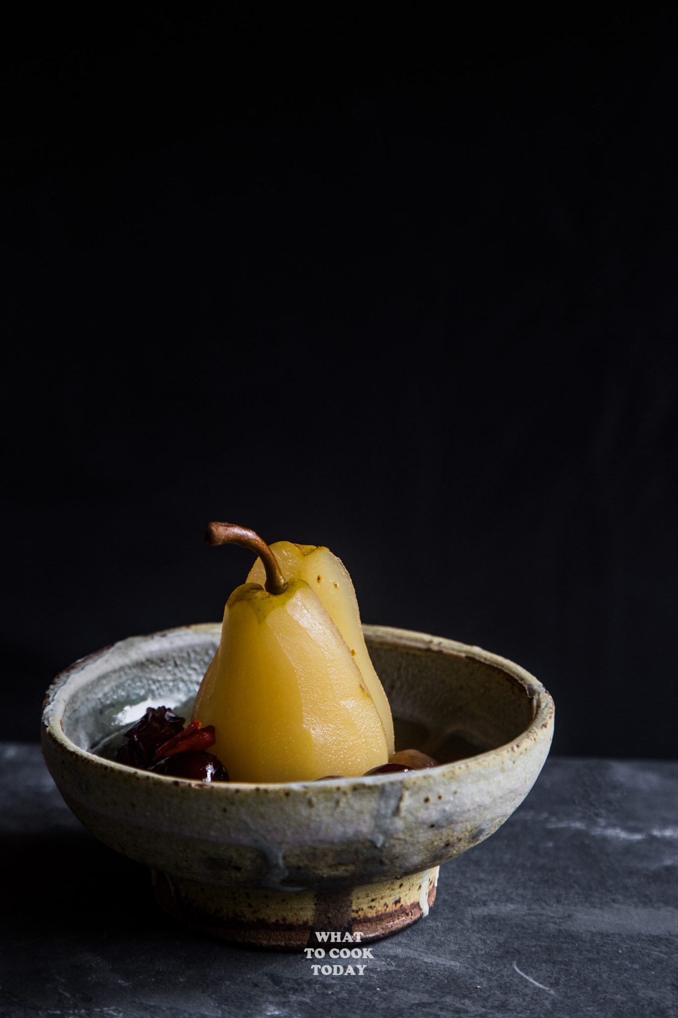 longan, red dates, goji berries poached pears standing up in a ceramic bowl